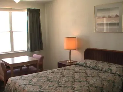 a hotel room with a bed and a desk and a window at Hometown Inn Galion in Galion