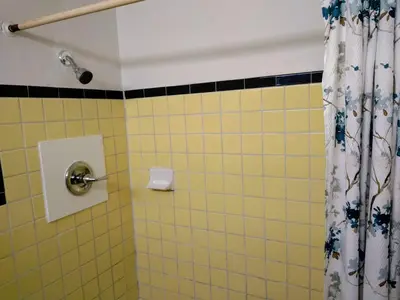 a yellow tiled bathroom with a shower curtain at Davis Motel in North Lima