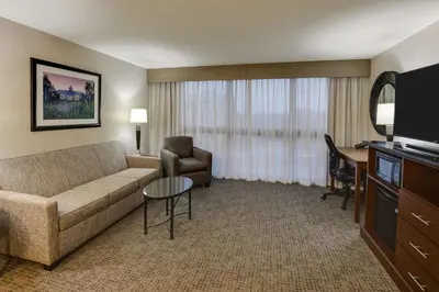 a living room with a couch and a chair and a desk at Drury Inn & Suites Columbus Dublin in Dublin