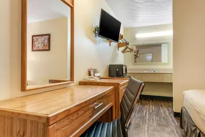 a hotel room with a desk and a mirror at Rodeway Inn Jeffersonville - Washington Court House in Jeffersonville