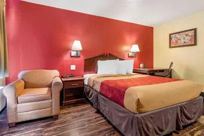 a hotel room with a bed and a chair at Rodeway Inn Jeffersonville - Washington Court House in Jeffersonville