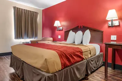 a hotel room with a large bed with red walls at Rodeway Inn Jeffersonville - Washington Court House in Jeffersonville