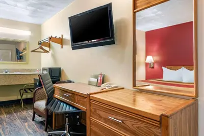 a room with a desk with a mirror and a bed at Rodeway Inn Jeffersonville - Washington Court House in Jeffersonville