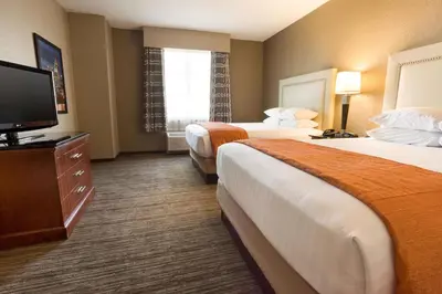 a hotel room with two beds and a flat screen tv at Drury Inn & Suites Cincinnati Sharonville in Sharonville