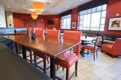 a restaurant with wooden tables and orange chairs at Drury Inn & Suites Columbus Grove City in Grove City