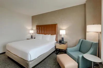 a hotel room with a bed and a chair at Drury Inn & Suites Dayton North in Dayton