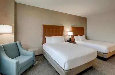 a hotel room with two beds and a chair at Drury Inn & Suites Dayton North in Dayton
