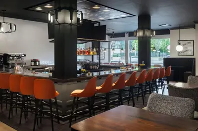 a bar in a restaurant with orange chairs at The Westin Great Southern Columbus in Columbus