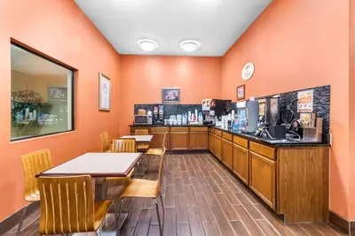 a restaurant with orange walls and a counter and chairs at Super 8 by Wyndham Bellefontaine in Bellefontaine