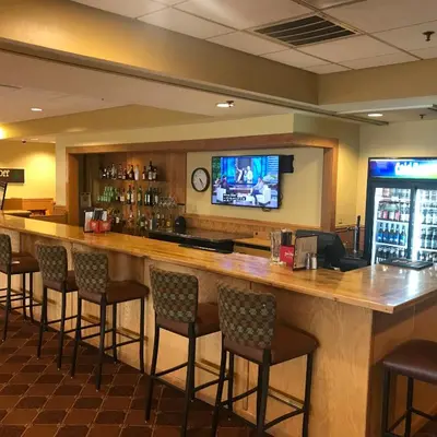 a bar in a restaurant with chairs and a tv at Days Inn & Suites by Wyndham Sutton Flatwoods in Sutton