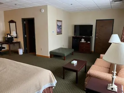 a hotel room with a bed and a flat screen tv at Days Inn & Suites by Wyndham Sutton Flatwoods in Sutton