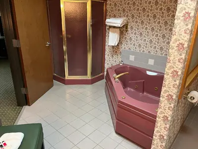 a bathroom with a pink tub and a shower at Days Inn & Suites by Wyndham Sutton Flatwoods in Sutton