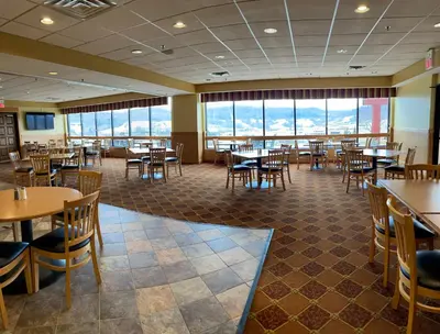 a dining room with tables and chairs and windows at Days Inn & Suites by Wyndham Sutton Flatwoods in Sutton