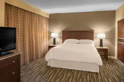 a bedroom with a large bed and a flat screen tv at Sheraton Suites Akron Cuyahoga Falls in Cuyahoga Falls