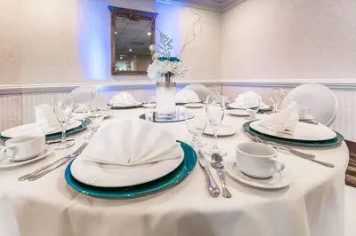 a table with white plates and napkins and a vase with flowers at Quality Inn & Suites Richfield in Richfield