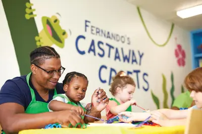 a man and two children playing with beads at a table at Castaway Bay by Cedar Point Resorts in Sandusky