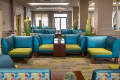 a waiting room with blue chairs and tables at Cedar Point's Express Hotel in Sandusky