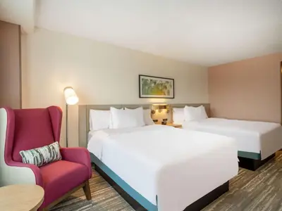 a hotel room with two beds and a red chair at Hilton Garden Inn Toledo Downtown in Toledo
