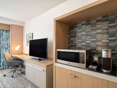 a hotel room with a desk with a microwave and a television at Hilton Garden Inn Toledo Downtown in Toledo