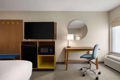 a hotel room with a bed and a desk and a television at Days Inn by Wyndham Hillsboro in Hillsboro
