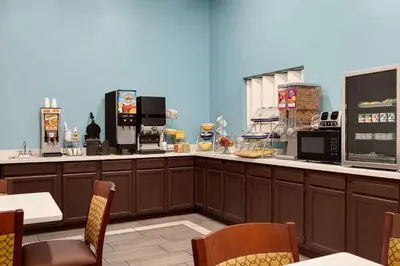 a restaurant with a counter with appliances and tables and chairs at Days Inn by Wyndham Hillsboro in Hillsboro
