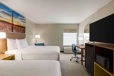 a hotel room with two beds and a flat screen tv at Days Inn by Wyndham Hillsboro in Hillsboro