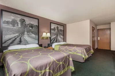 a hotel room with two beds and paintings on the wall at Super 8 by Wyndham Carrollton in Carrollton