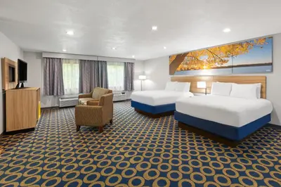 a hotel room with two beds and a chair at Days Inn by Wyndham Wauseon in Wauseon
