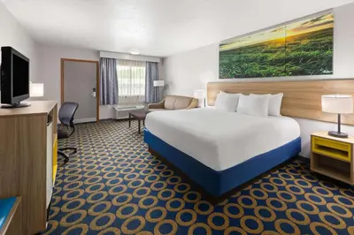 a hotel room with a bed and a flat screen tv at Days Inn by Wyndham Wauseon in Wauseon