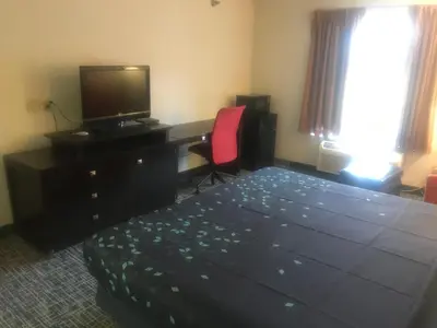 a bedroom with a bed and a desk with a television at Pier Inn in Luna Pier