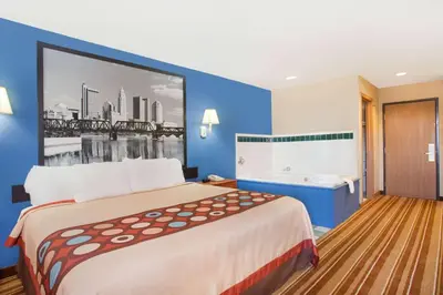 a hotel room with a large bed and a bath tub at Super 8 by Wyndham Defiance in Defiance