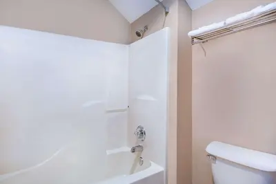 a white bathroom with a shower and a toilet at Super 8 by Wyndham Defiance in Defiance