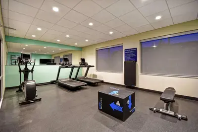 a gym with cardio equipment and a large screen at Tru By Hilton Cincinnati Airport South Florence in Florence