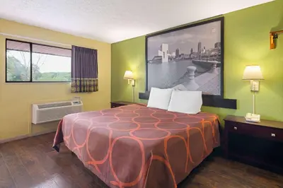 a hotel room with a bed with a large picture on the wall at Super 8 by Wyndham Youngstown Girard in Youngstown