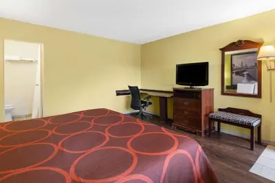a hotel room with a bed and a desk and a television at Super 8 by Wyndham Youngstown Girard in Youngstown