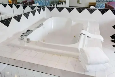 a white bath tub in a bathroom with black and white tiles at Super 8 by Wyndham Canonsburg/Pittsburgh Area in Canonsburg