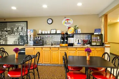 two tables and chairs in a restaurant with a counter at Super 8 by Wyndham Adrian in Adrian