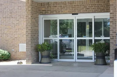 a glass door of a building with two potted plants at Super 8 by Wyndham Adrian in Adrian