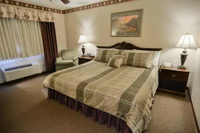 a hotel room with a bed and a chair at Hearthstone Inn & Suites in Cedarville