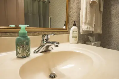 a bathroom sink with a bottle of soap and a mirror at Hearthstone Inn & Suites in Cedarville