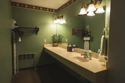 a green bathroom with a sink and a mirror at Hearthstone Inn & Suites in Cedarville