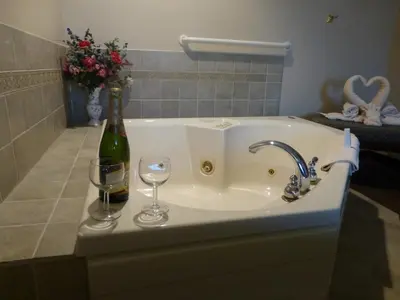 a bathroom sink with a bottle and two wine glasses at Hearthstone Inn & Suites in Cedarville