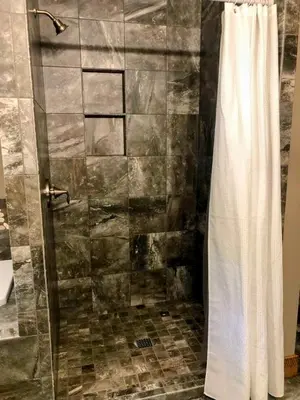 a shower with a glass door in a bathroom at Sojourner's Lodge & Log Cabin Suites in Dundee