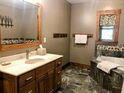 a bathroom with a sink and a tub and a mirror at Sojourner's Lodge & Log Cabin Suites in Dundee