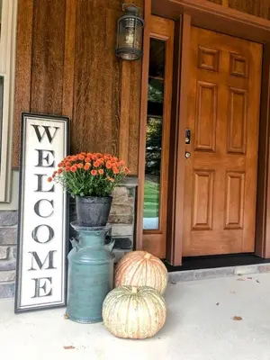 a porch with a pumpkin and a vase with a plant at Sojourner's Lodge & Log Cabin Suites in Dundee