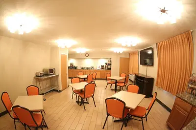 a dining room with tables and chairs and a kitchen at Super 8 by Wyndham Portsmouth in Portsmouth