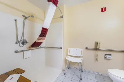 a bathroom with a toilet and a chair in it at Red Roof Inn Auburn in Auburn
