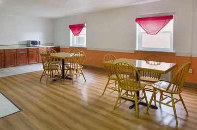 a dining room with tables and chairs and a kitchen at Motel 6-Sidney, OH in Sidney