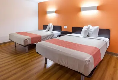 two beds in a room with orange walls and wood floors at Motel 6-Sidney, OH in Sidney