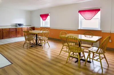a dining room with tables and chairs and a kitchen at Motel 6-Sidney, OH in Sidney